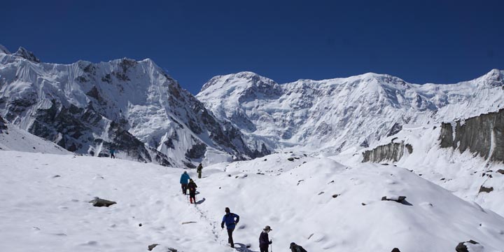 キルギス最高峰天山山脈ポベーダ（Pobeda Peak 中央から少し右の峰：7,439m）を望み，南イニルチェク氷河のベースキャンプ（Southern Inylchek BC：4,000m）周辺を歩く
